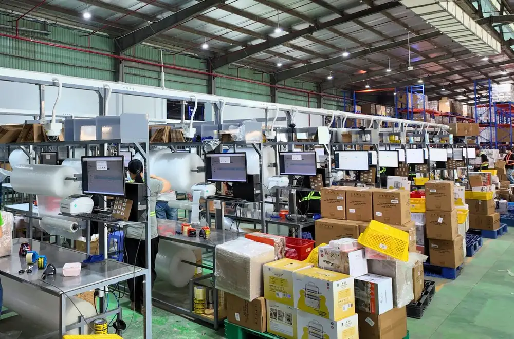 Dãy bàn đóng gói có máy tính và thiết bị quét mã trong kho Onflow Fulfillment