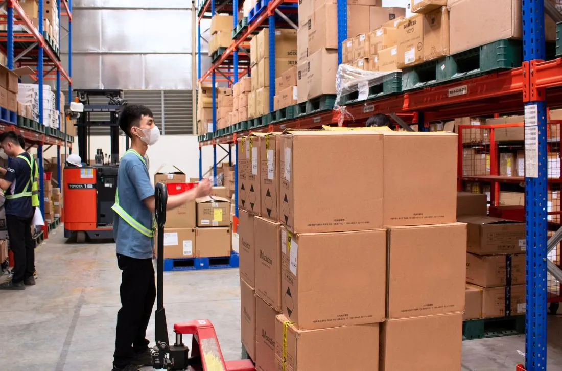 Nhân viên kho Onflow Fulfillment vận chuyển hàng bằng xe nâng tay giữa các dãy kệ